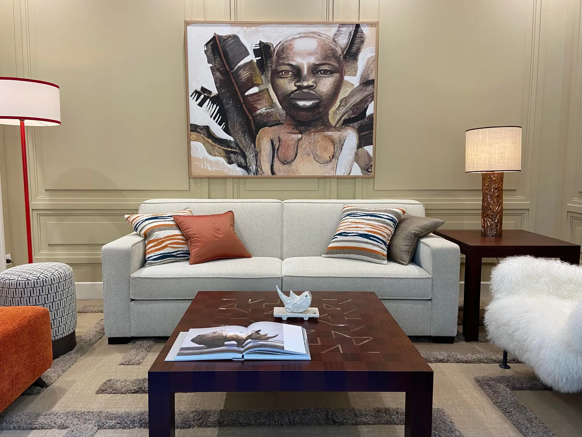 Lo showroom: un divano grigio coi cuscini a righe, il tavolino basso, un quadro grande e le lampade accese