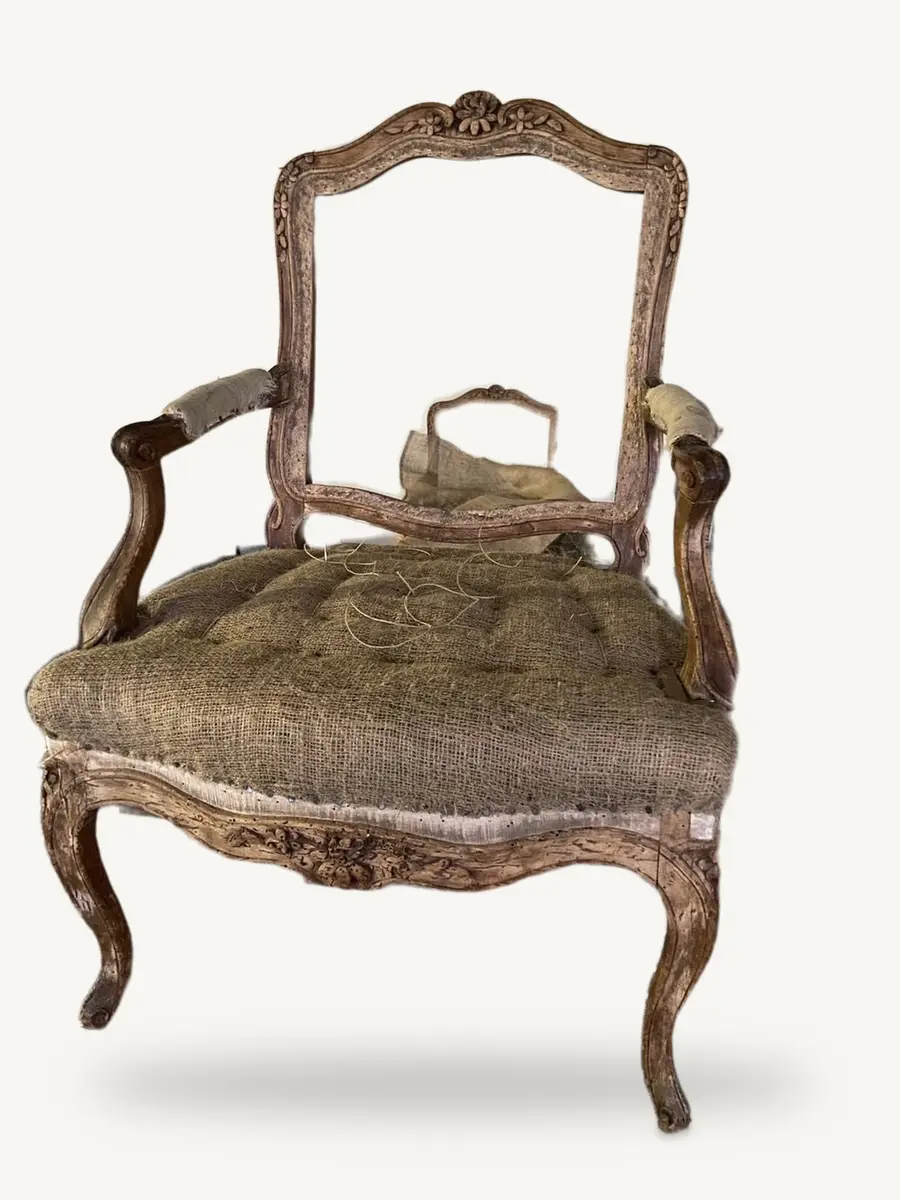 La poltrona prima del restauro, senza la stoffa: restano l'imbottitura vecchia sotto la juta e il legno consumato